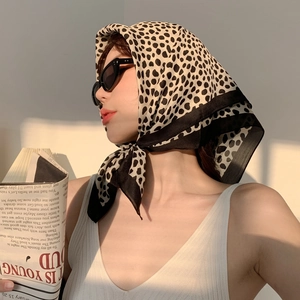 Close-up of leopard and polka dot print silk scarf tied in hair with sunset lighting
