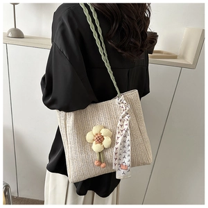 Detail of hand-woven straw tote bag with yellow flower charm and decorative scarf