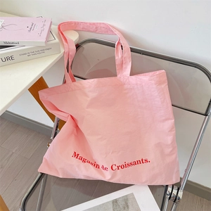 Close-up of pink canvas tote bag with red Magasin de Croissants text on acrylic chair