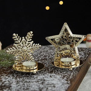 Golden iron snowflake and star candle holders on snowy wood for Christmas decor