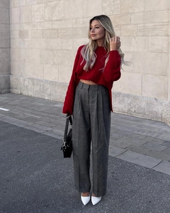 Close-up of red cable knit sweater texture paired with grey wide-leg trousers and white heels