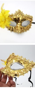 Detail of gold sequin masquerade mask featuring yellow side flower and soft feathers