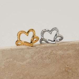 Minimalist hollow heart rings in gold and silver finish on elegant marble surface