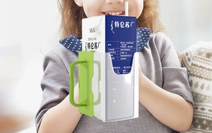 Close-up of a child holding the green adjustable anti-squeeze milk carton holder with handles