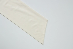Detailed close-up of beige knitted fabric texture and ring metal buckle on the skirt set