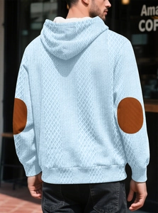 Détail du sweat à capuche bleu clair avec coudières marron et tissu jacquard texturé