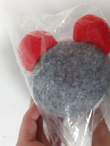 Detail of grey gnome plush toy with red ears in clear protective plastic packaging