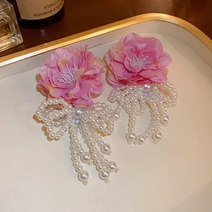 Pink floral earrings with long pearl tassel and bow in elegant gold-trimmed tray
