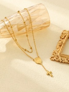 Detail of 18k gold plated rosary necklace with beads, religious medal and cross pendant