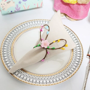 Detail of a pink floral napkin ring with colored flower buds on a ceramic plate