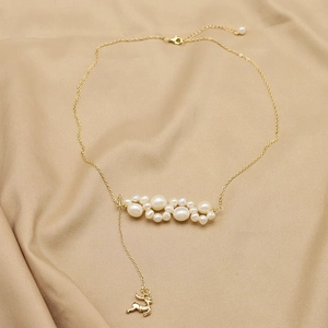 Natural pearl necklace with golden elk pendant on soft silk background, vintage style