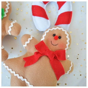 Macro view of plush gingerbread man ornament with red bow and stripe candy cane