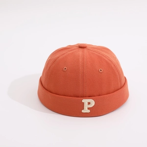 Close-up of brick red cotton brimless cap for children with white P letter embroidery