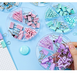 Macro shot of macaron colored binder clips and paperclips in a round divider box