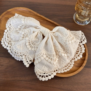 Elegant beige lace embroidery bow hair clip on a rustic wooden tray for women