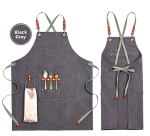 Detail of dark gray canvas work apron showing functional pockets and leather straps