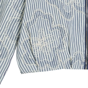 Macro detail of blue and white striped jacket with floral embroidery and metal zipper