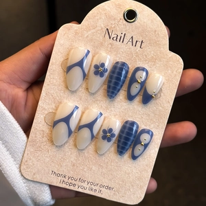 Detail of almond press-on nails with crocodile pattern and floral blue embellishments