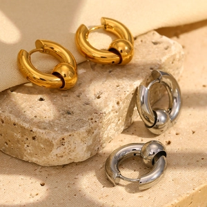 Detail view of gold and silver beaded hoop earrings on a natural stone surface