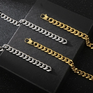 Classic 11mm Cuban link bracelets in gold and silver steel on a black textured display case