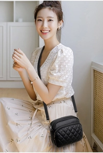 Detail of a black quilted crossbody bag with adjustable leather and chain shoulder strap