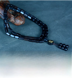 Detailed macro of dark sandalwood beads bracelet with golden engraved character charm