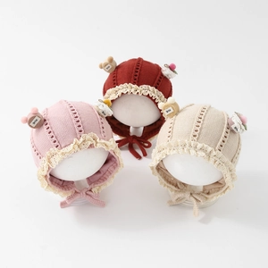 Winter knitted baby hats with lace trim and bear decor in pink, red, and cream white