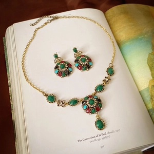 Detailed flat lay of vintage gold jewelry set with multi-colored gems on art book