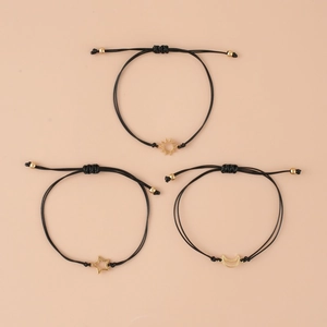 Three-piece set of adjustable woven bracelets with gold sun moon and star charms on beige background