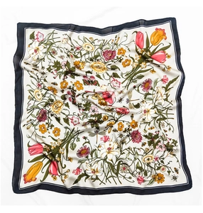 Detailed close-up of silk scarf showing elegant floral prints and butterflies on cream fabric