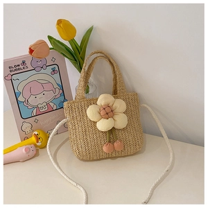 Detail of handmade straw crossbody bag with large plush flower and fuzzy pompom charms