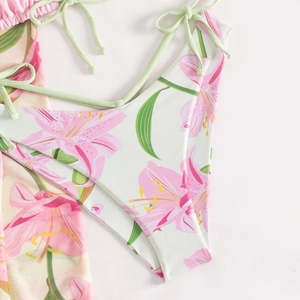 Dettaglio slip bikini con stampa floreale di gigli rosa e lacci laterali verde menta