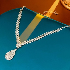 Detail der silbernen Tropfenkette mit glitzernden Kristallen auf blauem Sockel