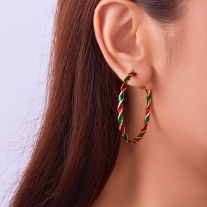 Detailed close-up of red, green, and gold twisted hoop earrings with festive spiral design