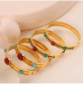 Detail of vintage hollow gold bangle with inlaid red, green and blue gemstones