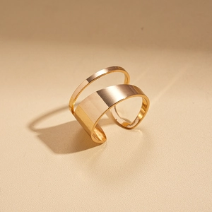 Detailed macro view of minimalist gold irregular layered rings on a textured cream backdrop