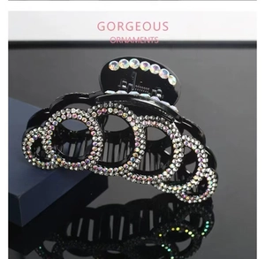 Detail of a large black hair claw clip decorated with sparkling rainbow rhinestones