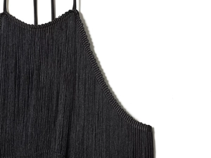 Close-up of black velvet dress featuring dense fringe detailing and woven textures