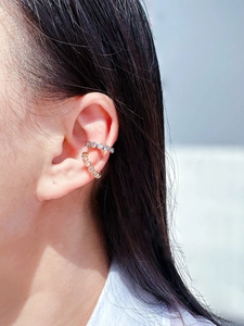 Close-up of gold and silver ear bone clips with zircon stones on female ear