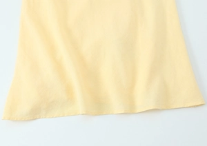 Makroaufnahme der Saumnaht aus hochwertigem Leinenstoff an cremegelbem Kleid