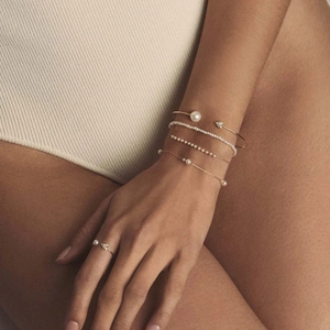Detail shot of 18k gold stainless steel pearl bracelets and open ring on a model's hand