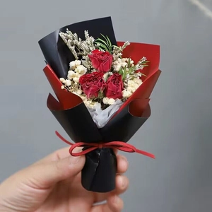 Detail of mini bouquet with three red dried roses and baby's breath in black-red wrapping