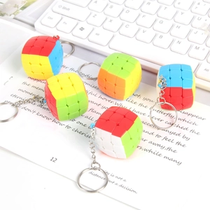 Detailed view of 3x3 mini cube keychains with metal chains on a white keyboard desk
