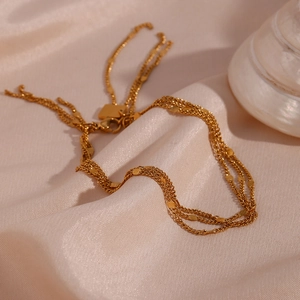 Detail of gold multi-layer sequin tassels displayed on soft pink silk with shells