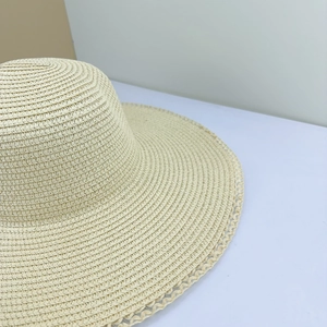 Close-up of beige straw sun hat featuring intricate spiral weave and lace edge detailing