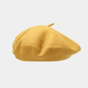 Detailed texture of a bright yellow wool beret hat shown against a clean background