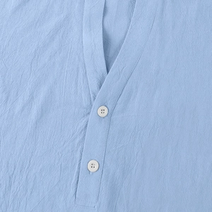 Macro detail of sky blue linen shirt collar featuring white buttons and textured fabric