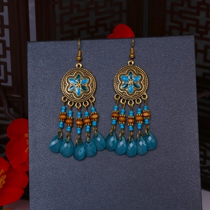Dettaglio di orecchini boho con perline turchesi e fiori in bronzo in stile vintage
