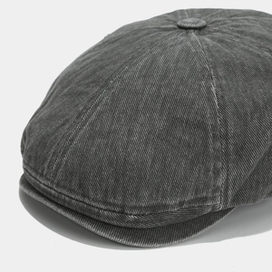Close-up of dark grey newsboy cap showing washed cotton twill fabric and top button