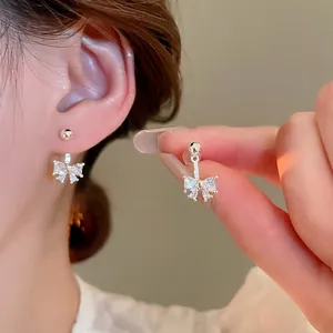 Sparkling zircon bowknot stud earrings in silver finish worn by a model